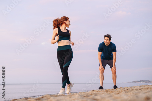Full size couple young two friends strong sporty sportswoman sportsman woman man wear sport clothes warm up training running on sand sea ocean beach outside jog on seaside in summer day cloudy morning