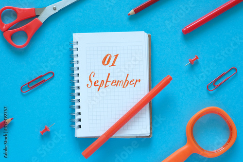 Flat lay. Blue background. In the center is a notebook with the text "September 1". Around the stationery. Knowledge day, study, school, college.