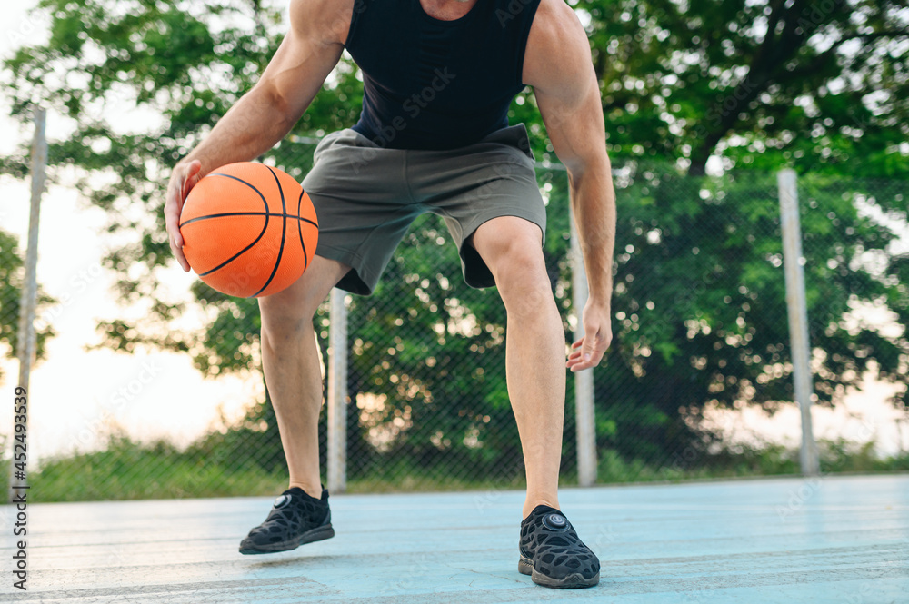 Naklejka premium Cropped close up muscular young sporty sportsman man 20s wear black sports clothes training basketball ball handling drills play at basketball game playground court Outdoor courtyard sport concept.