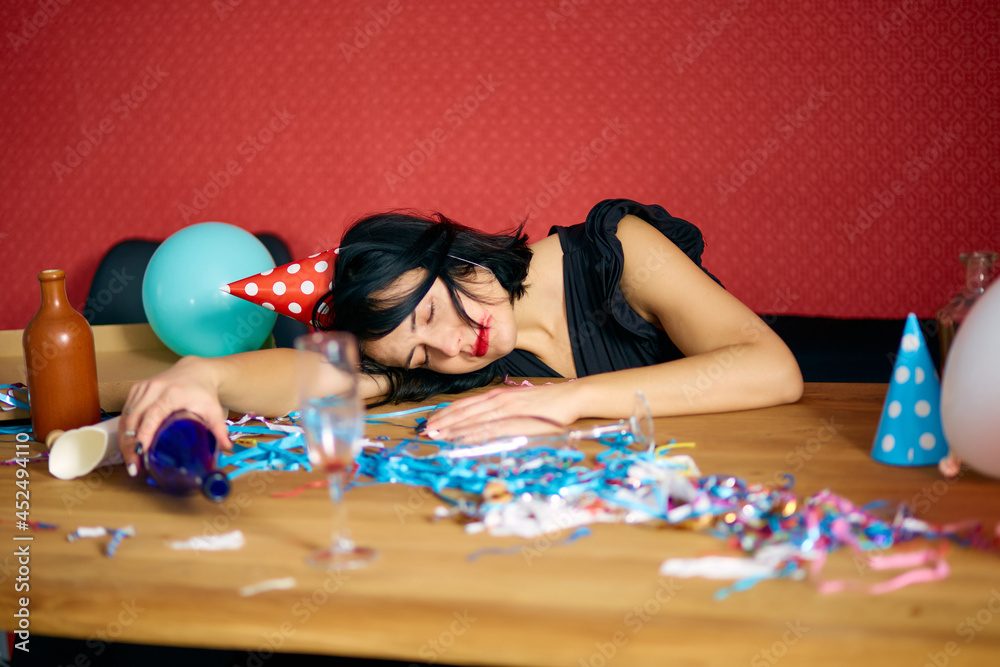 Young woman with sleeping at table in messy room after birthday party Young woman with sleeping at table in messy room after birthday party