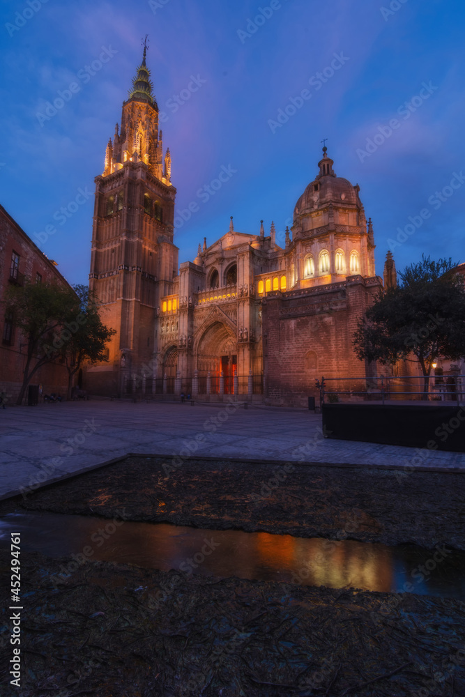 Cityscape in old city at sunset; Cathedral square in the old town of Toledo with reflection in the water of the fountain - artificial lake, World Heritage Site, Spain. Vertical view 
