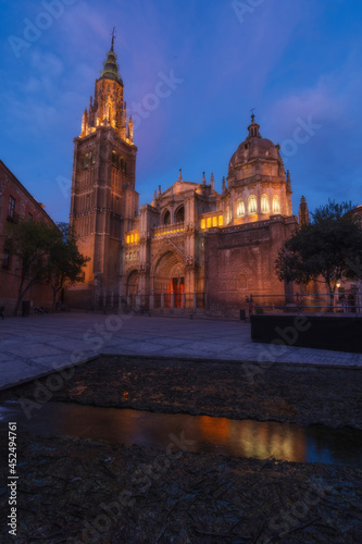 Cityscape in old city at sunset; Cathedral square in the old town of Toledo with reflection in the water of the fountain - artificial lake, World Heritage Site, Spain. Vertical view 