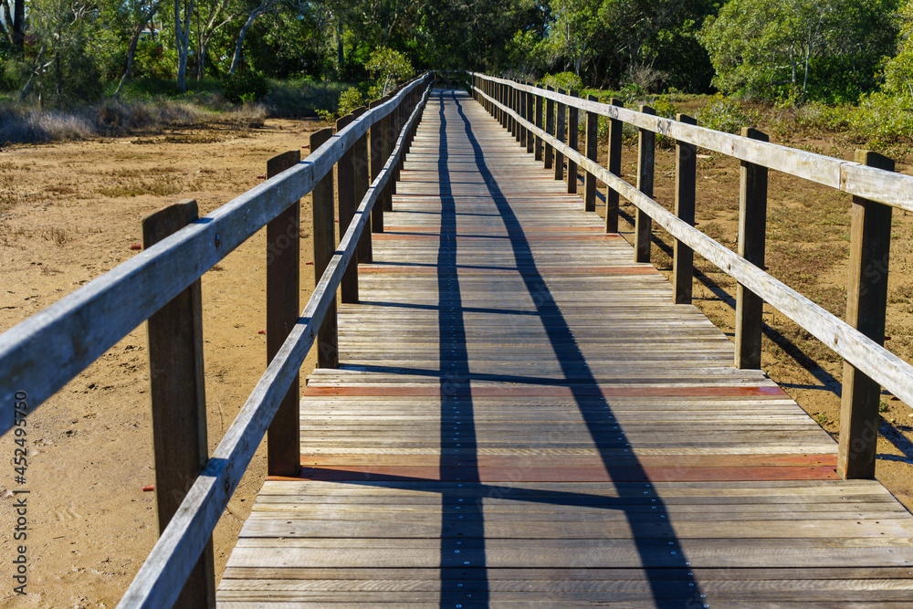 Perspective view of a wooden boardwalk crossing the muddy wetlands at Lota, Queensland, Australia.