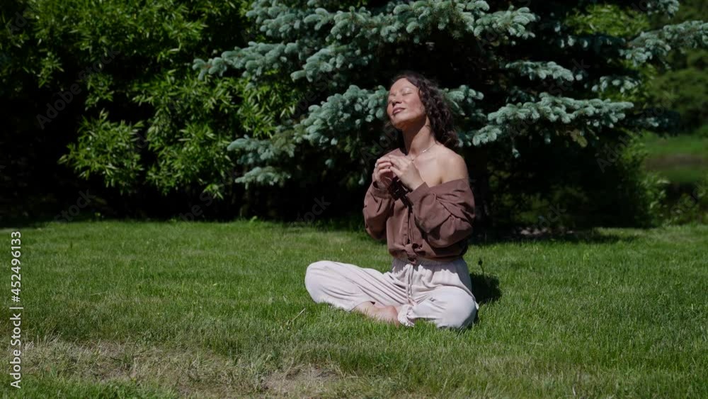 an Asian woman meditates in nature in a park on a sunny day sitting on the grass in the lotus position an Asian woman meditates in nature in a park on a sunny day sitting on the grass in the lotus position