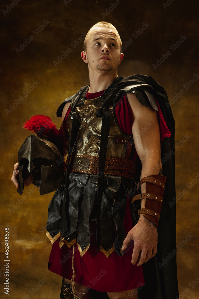 Full length portrait of medieval person, brutal man, warrior or knight in war equipment isolated on vintage dark background. Comparison of eras, art, history, retro style concept