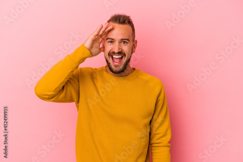 Young caucasian man with tattoos isolated on pink background shouts loud, keeps eyes opened and hands tense.