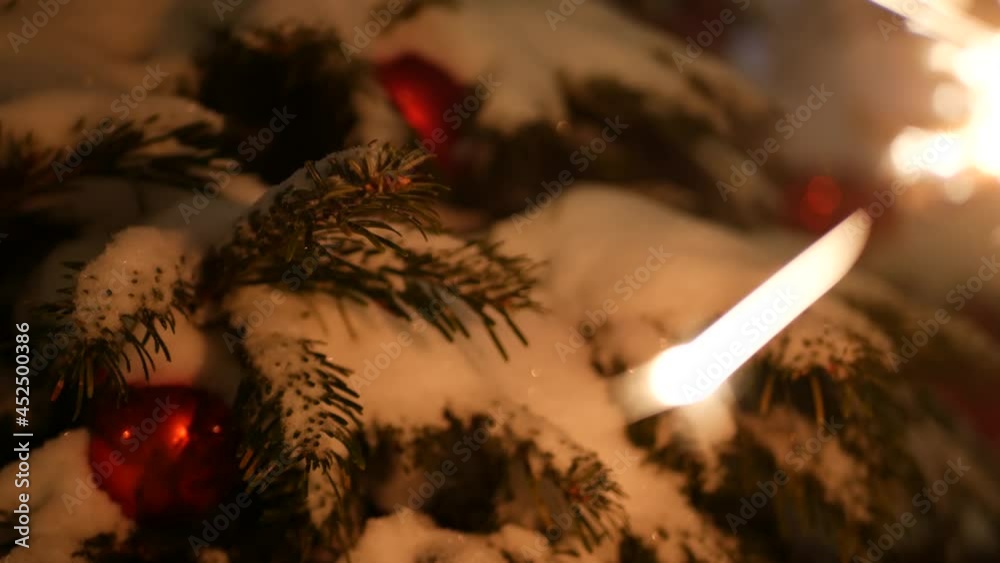 Christmas tree in snow, sparkler firework burning, New Year or Xmas bengal light. Winter holiday magic, sparkles, flakes, golden stars. Spruce, pine or fir in snowflakes. Seamless looped cinemagraph.