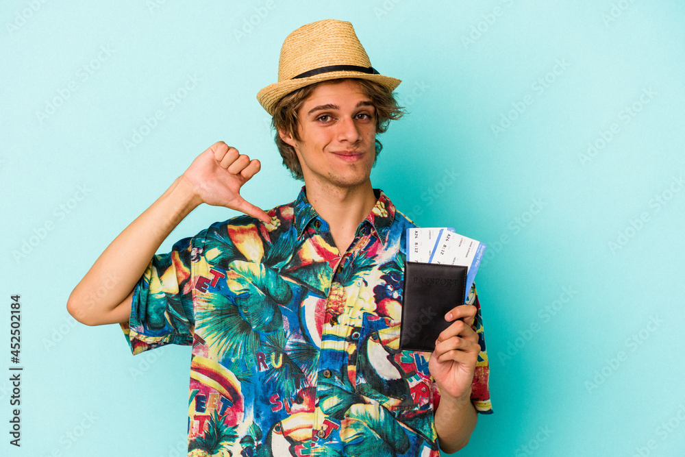 Young caucasian man with makeup holding passport isolated on blue background feels proud and self confident, example to follow. Young caucasian man with makeup holding passport isolated on blue background feels proud and self confident, example to follow.