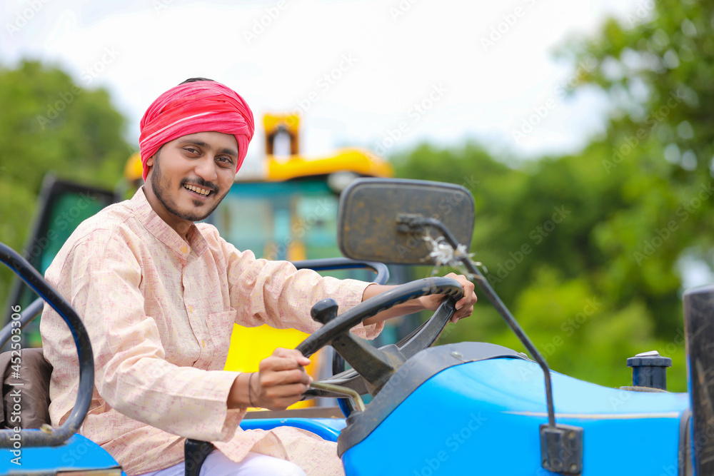 Technology and people concept, Portrait of young indian farmer with tractor
