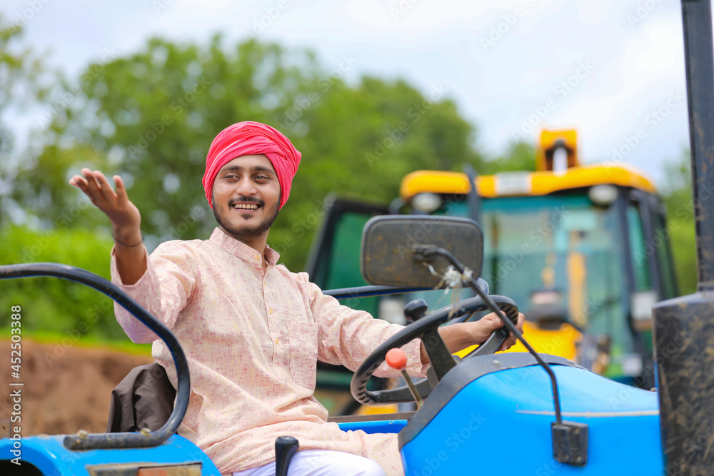 Technology and people concept, Portrait of young indian farmer with tractor Technology and people concept, Portrait of young indian farmer with tractor