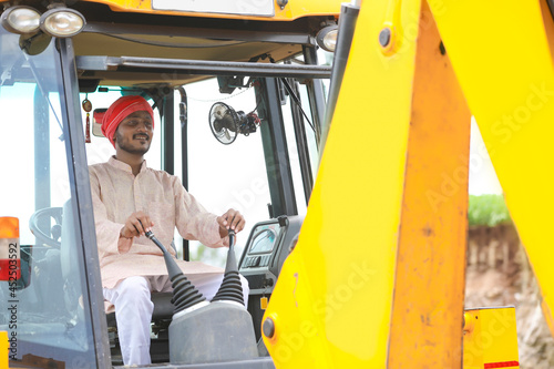 Indian man working with heavy equipment vehicle at construction site.