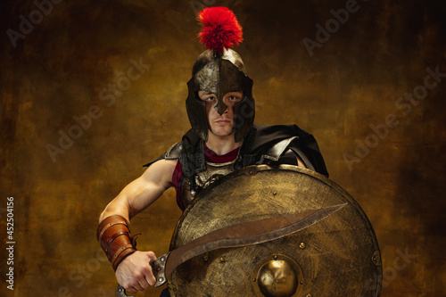 Close up of medieval person, brutal man, warrior or knight in war equipment isolated on vintage dark background. Comparison of eras, art, history, retro style concept