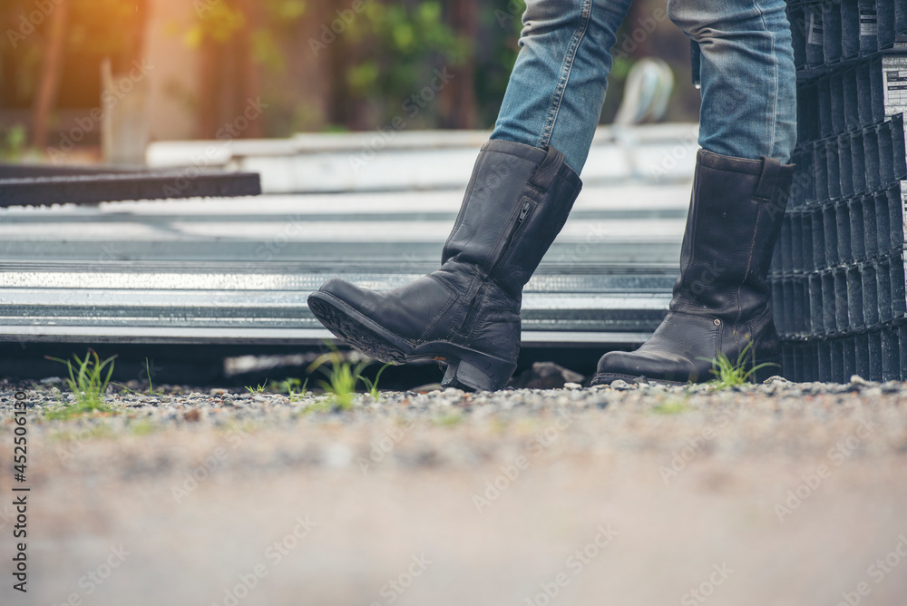 Women wear construction Boots safety footwear for worker at construction site. Woman Engineer Wear Jeans black Boots Worker standing at construction site. Engineer safety industry footwear walking