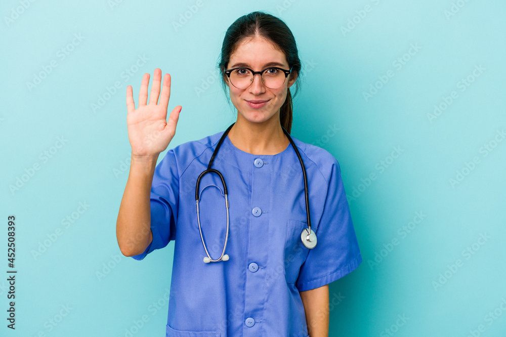 Young caucasian nurse isolated on blue background smiling cheerful showing number five with fingers. Young caucasian nurse isolated on blue background smiling cheerful showing number five with fingers.