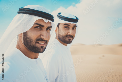 Two business men wearing traditional uae white kandura spending time in the desert of Dubai © oneinchpunch