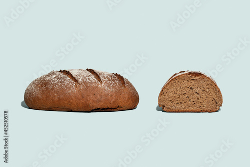 Fresh black sliced rye bread on light blue background.