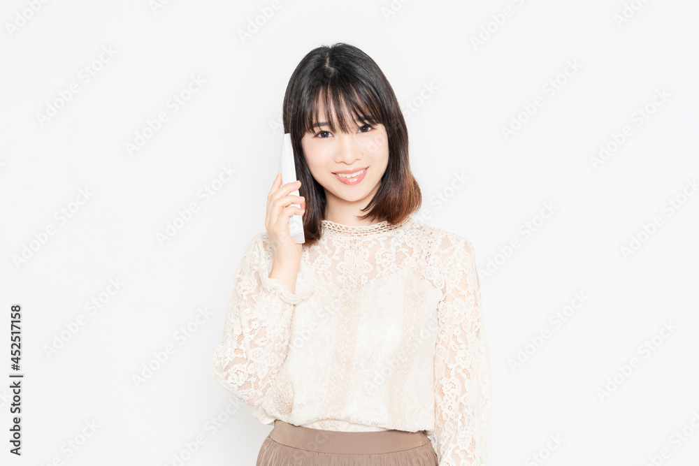 電話の子機を持って立っている女性 電話の子機を持って立っている女性