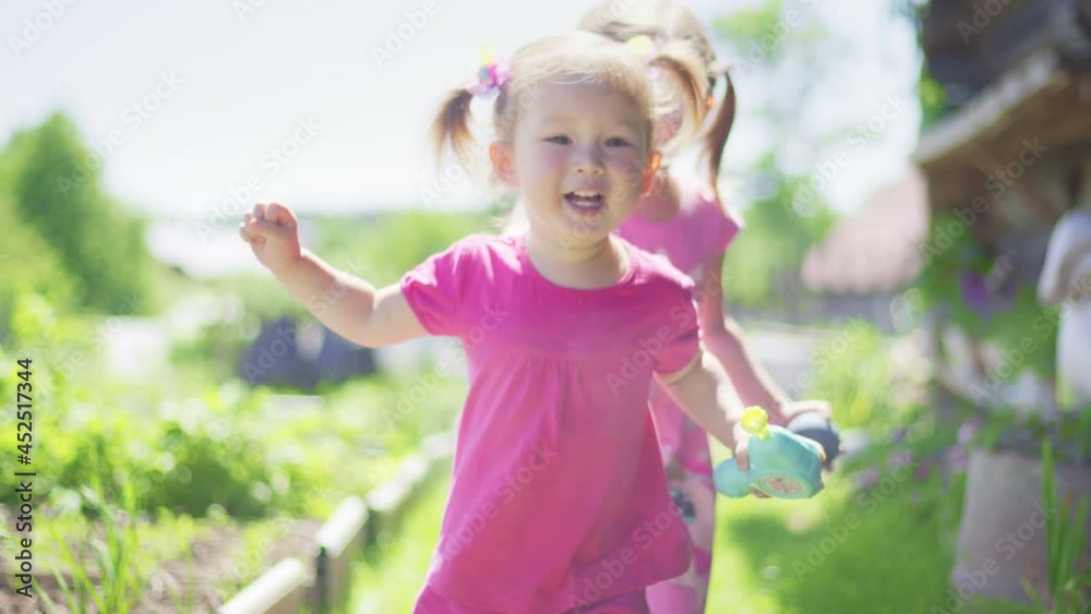 Two girls run in the summer garden and play with each other Two girls run in the summer garden and play with each other