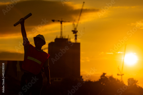 silhouette of engineer and construction site background at sunset