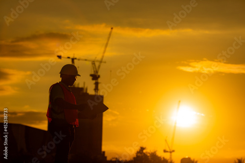 silhouette of engineer and construction site background at sunset