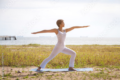 Women athletes exercise to burn fat with yoga and exercise on a yoga mat . Beautiful sporty fit yoga woman. doing yoga practice on the beach,healthy life and natural balance