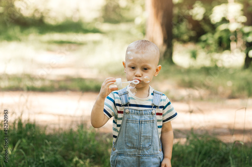 Little boy inflating soap bubbles in the summer in nature