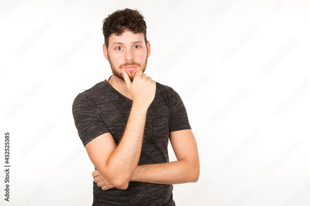 young caucasian man with brunette hair with beard thoughtful with hand on chin young caucasian man with brunette hair with beard thoughtful with hand on chin