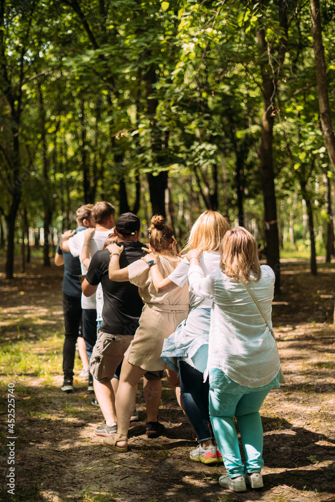 Team building exercise. People stand behind each other and the leader controls those who stand in front. Trust Exercise Understanding Team building exercise. People stand behind each other and the leader controls those who stand in front. Trust Exercise Understanding