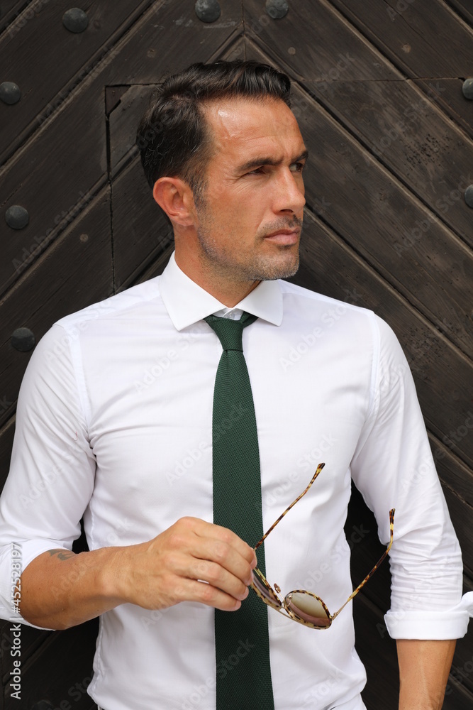 Bardzo przystojny, elegancki mężczyzna w białej koszuli i zielonym krawacie i okularach przeciwsłonecznych. - obrazy, fototapety, plakaty 