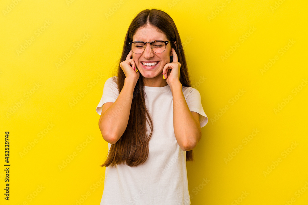 Young caucasian woman isolated on yellow background covering ears with hands. Young caucasian woman isolated on yellow background covering ears with hands.