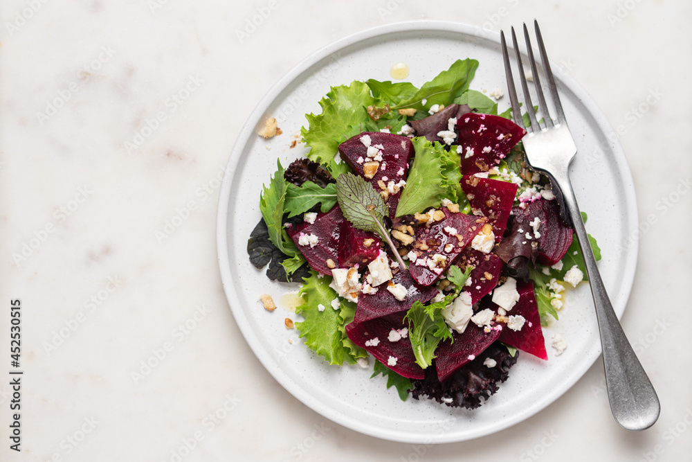 Beetroot salad with feta cheese and walnuts. Vegetable salad in plate on white marble background, top view Beetroot salad with feta cheese and walnuts. Vegetable salad in plate on white marble background, top view