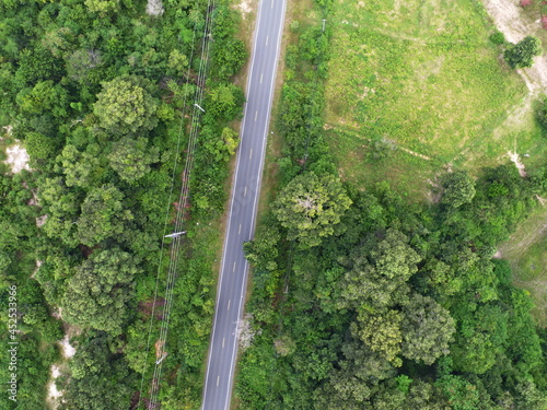 Aerial drone view of country road between green forest 