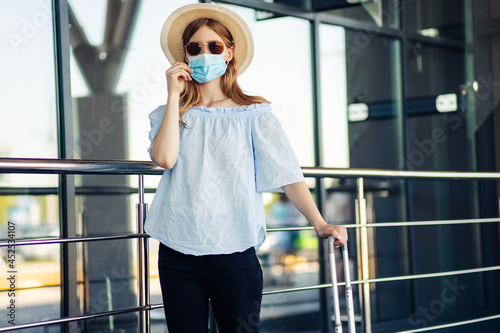 Young woman holding passport and tickets, wearing a protective mask in the city, Woman with a suitcase, Business travel during a pandemic © Shopping King Louie