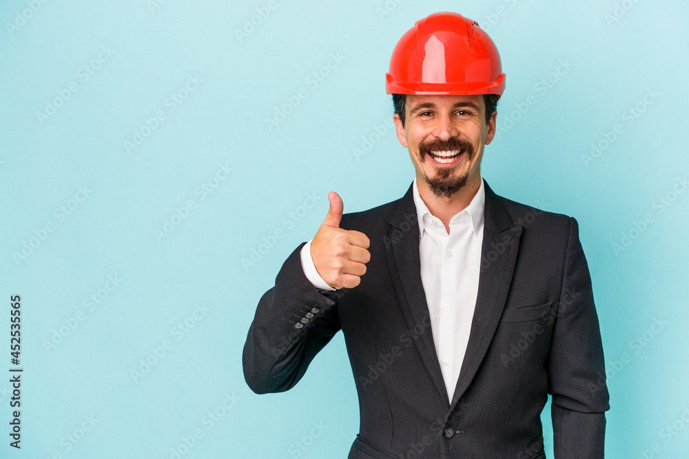 Young architect caucasian man isolated on blue background smiling and raising thumb up