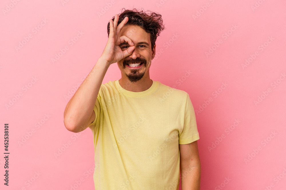 Young caucasian man isolated on pink background excited keeping ok gesture on eye. Young caucasian man isolated on pink background excited keeping ok gesture on eye.
