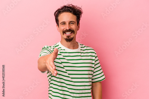 Young caucasian man isolated on pink background smiling and raising thumb up