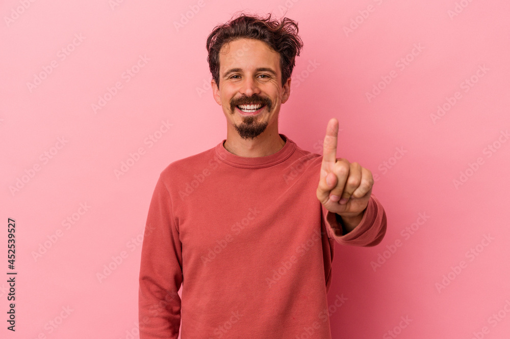 Young caucasian man isolated on pink background showing number one with finger. Young caucasian man isolated on pink background showing number one with finger.