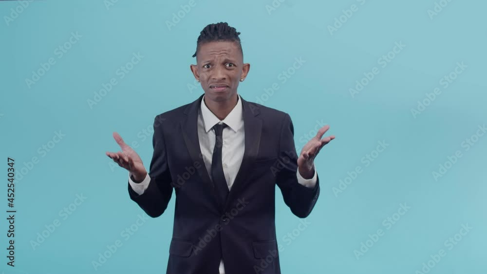 Disgruntled black male businessman indignantly makes a gesture with a crazy hand in the studio on blue background. Disgruntled black male businessman indignantly makes a gesture with a crazy hand in the studio on blue background.