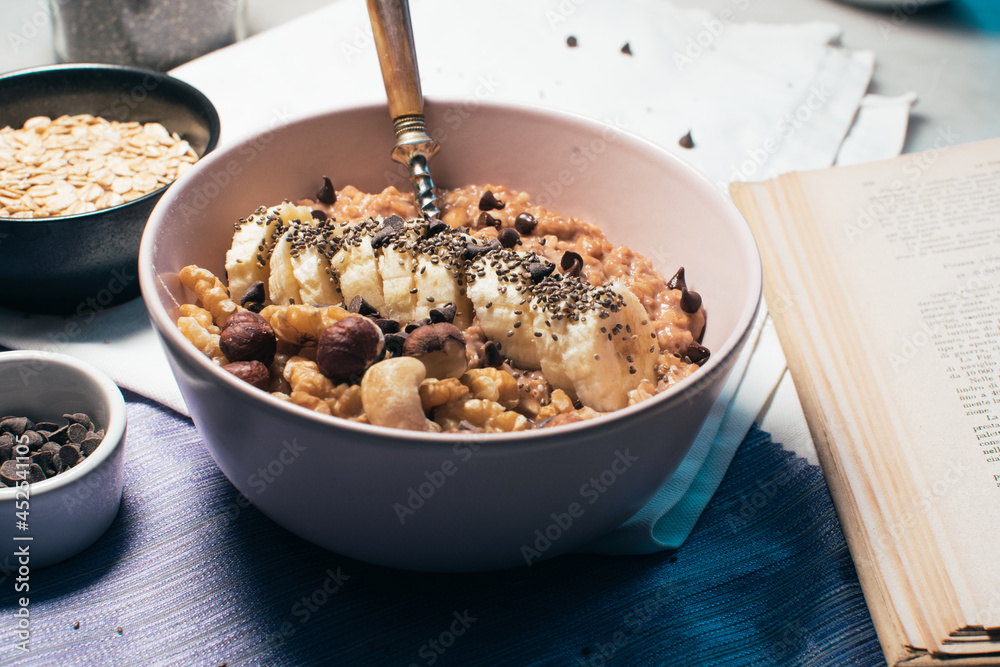 Bowl of oatmeal porridge with banana and nuts. Top view. Healthy vegan breakfast