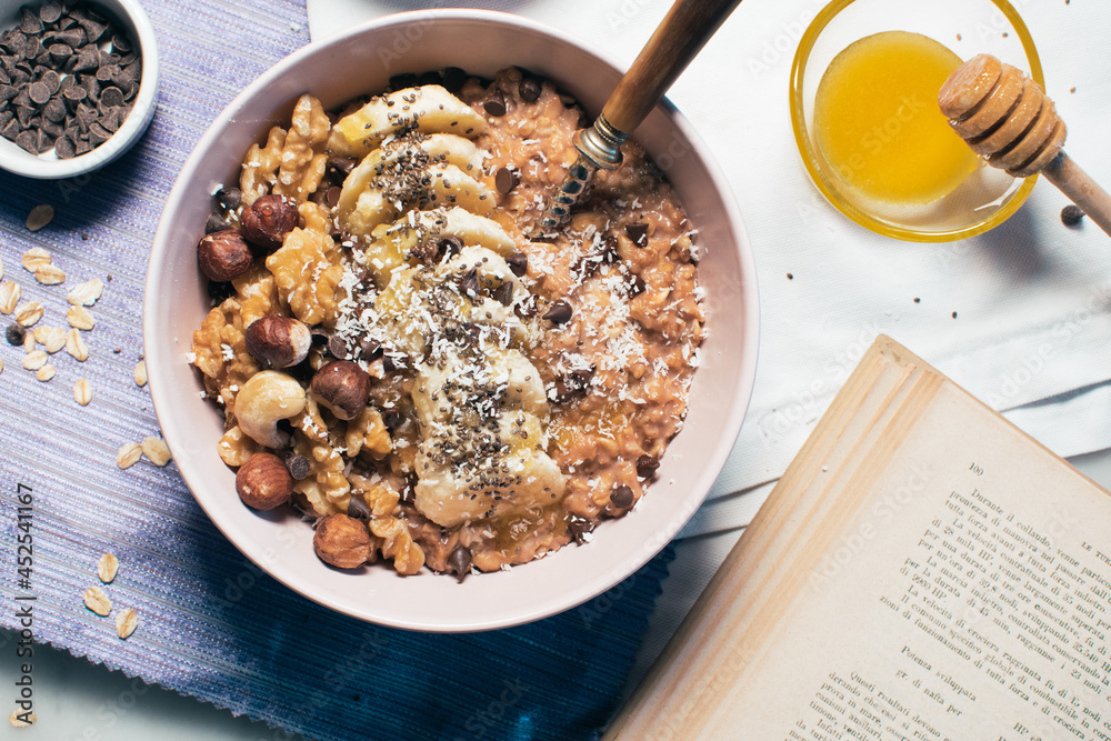 Bowl of oatmeal porridge with banana and nuts. Top view. Healthy vegan breakfast