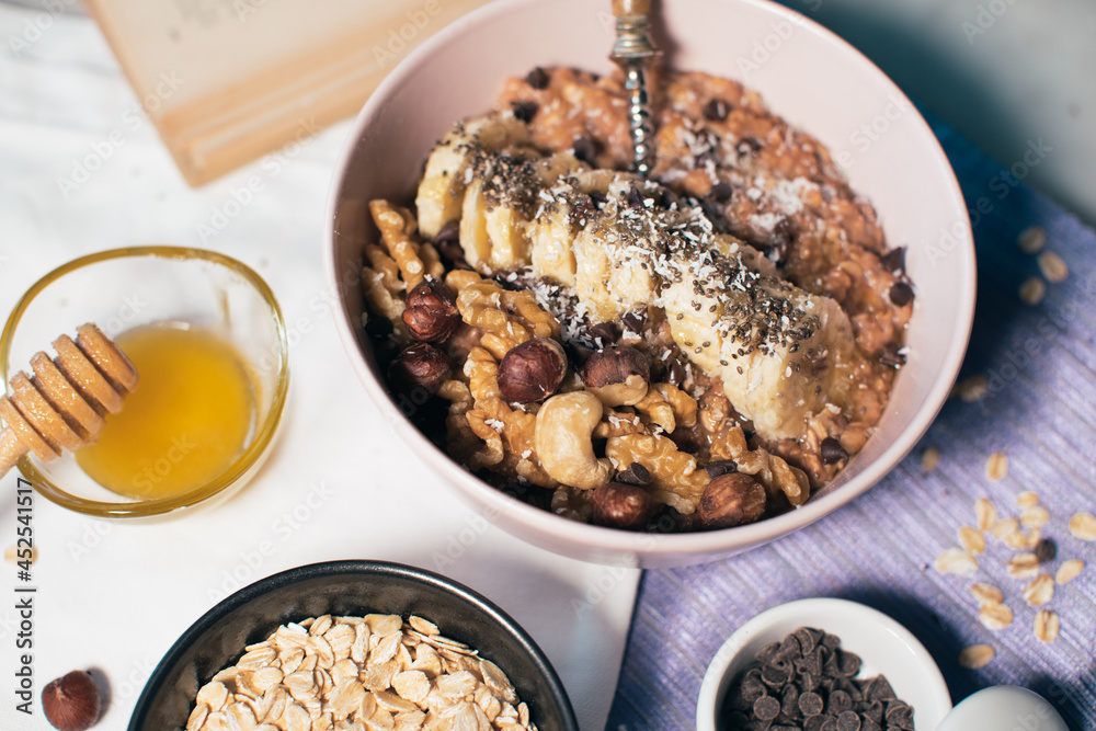 Bowl of oatmeal porridge with banana and nuts. Top view. Healthy vegan breakfast