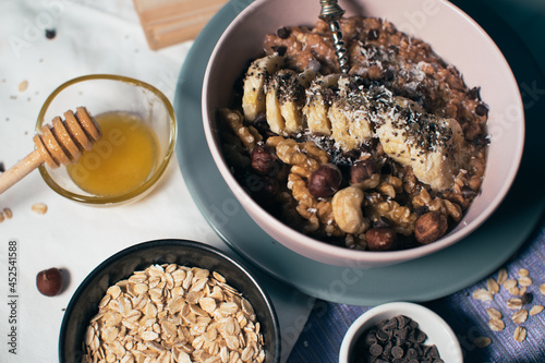 Bowl of oatmeal porridge with banana and nuts. Top view. Healthy vegan breakfast
