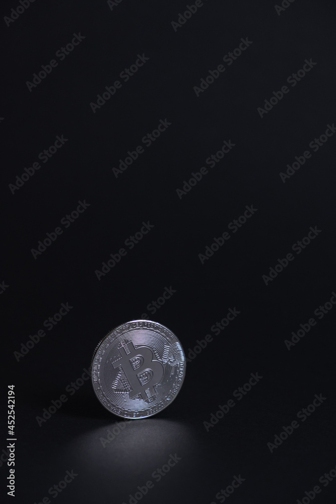 One BitCoin coin close-up with face on silver colour stand bottom centered on back background. Bitcoin BTC Digital crypto currency - Electronic Money. Digital coin international stock exchange. One BitCoin coin close-up with face on silver colour stand bottom centered on back background. Bitcoin BTC Digital crypto currency - Electronic Money. Digital coin international stock exchange.