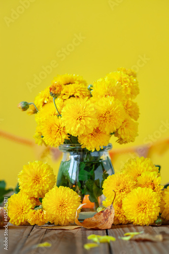 Billede på lærred Bouquet of beautiful yellow chrysanthemums on wood table on yellow background