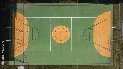 Multi-sport court (volleyball, futsal and basketball), in green and yellow, covered with net and a little dirty due to the weather. photo