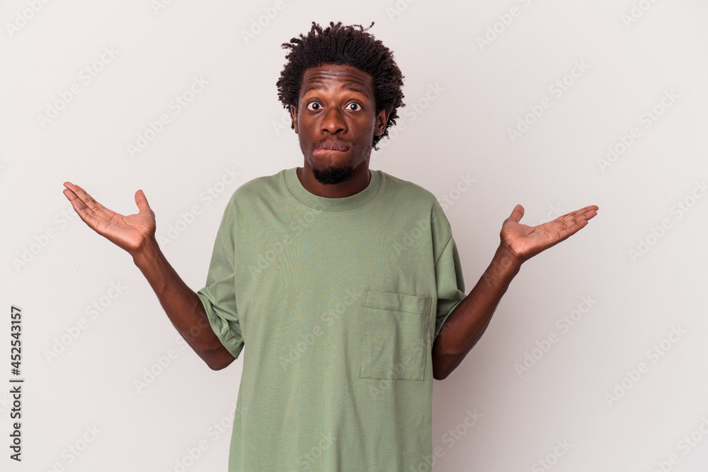 Young african american man isolated on white background confused and doubtful shrugging shoulders to hold a copy space. Young african american man isolated on white background confused and doubtful shrugging shoulders to hold a copy space.