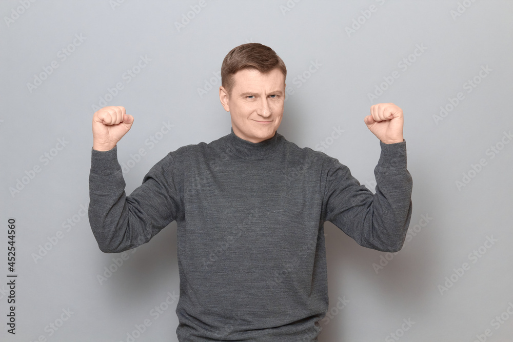 Portrait of happy proud mature man raising fists up in triumph