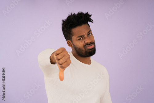 Young afro man showing thumb down to the camera.