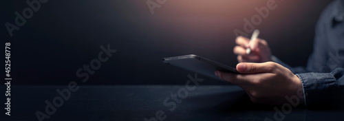 Businessman is working on Tablet or smartpad. stock business or work from home concept. dark tone