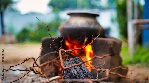 Selective focus, Outdoor Indian earthen cooking stove Countryside stove or Chulha or clay stove with a black colored circular vessel on it, photo
